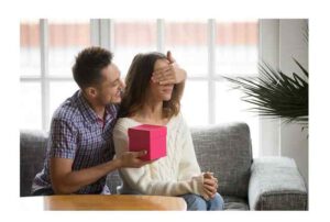 Loving boyfriend closing eyes of girlfriend presenting romantic surprise gift